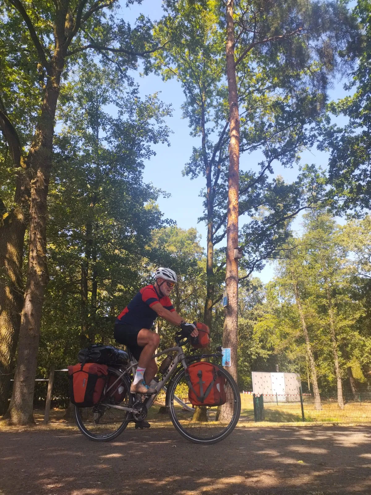 Jean-Pierre roule à vélo sous les arbres, avec ses sacoches