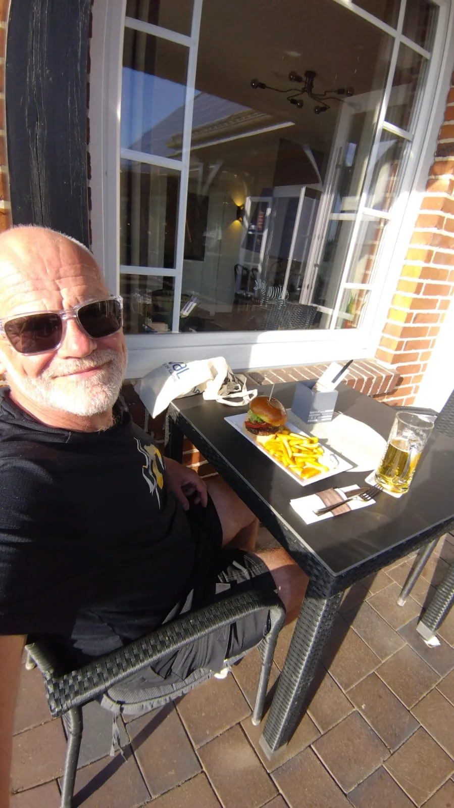 Jean-Pierre dîne avec un burger-frites à la terrasse d’un restaurant