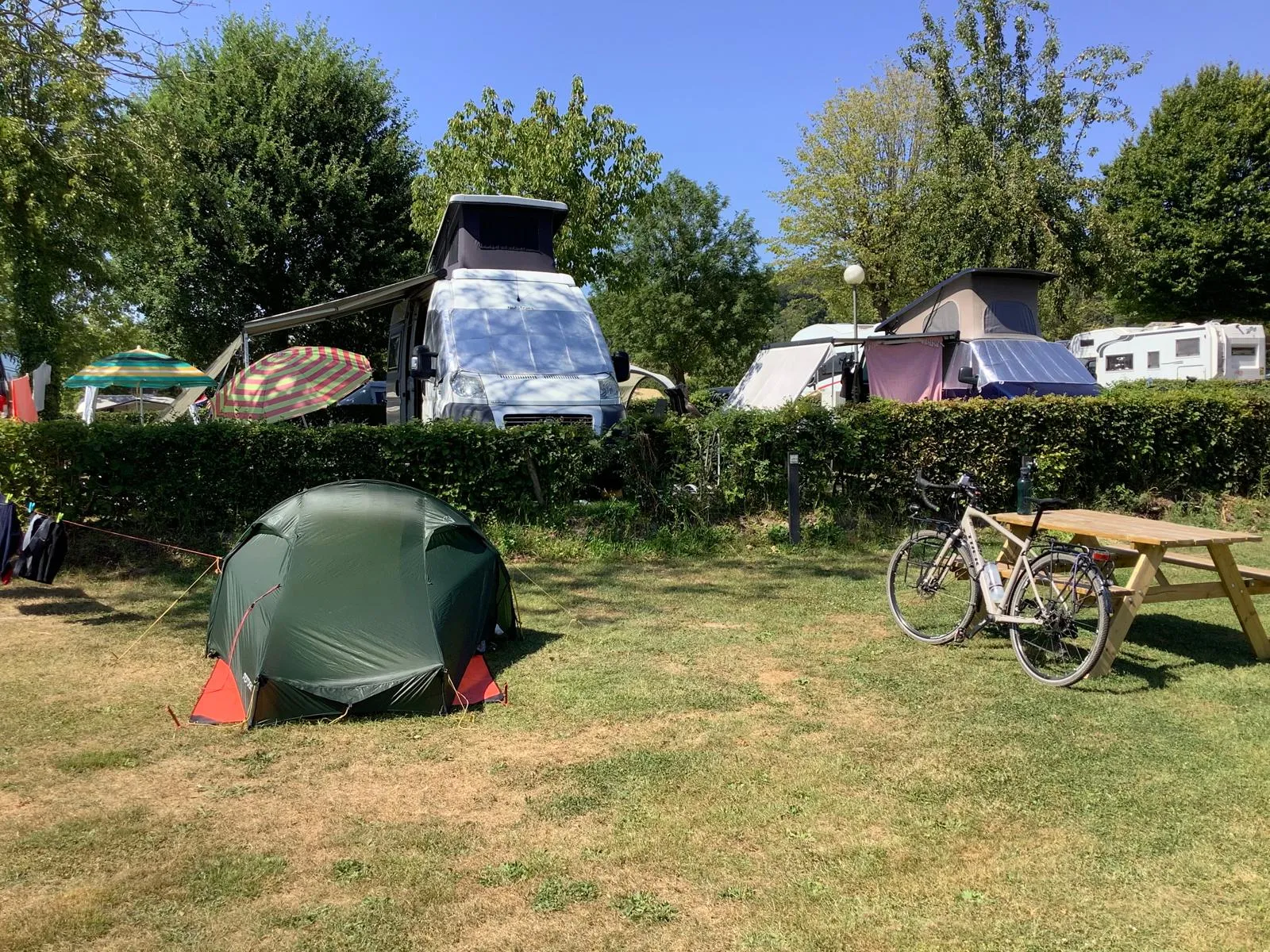 La tente et le vélo installés parmi les caravanes et les camping-cars