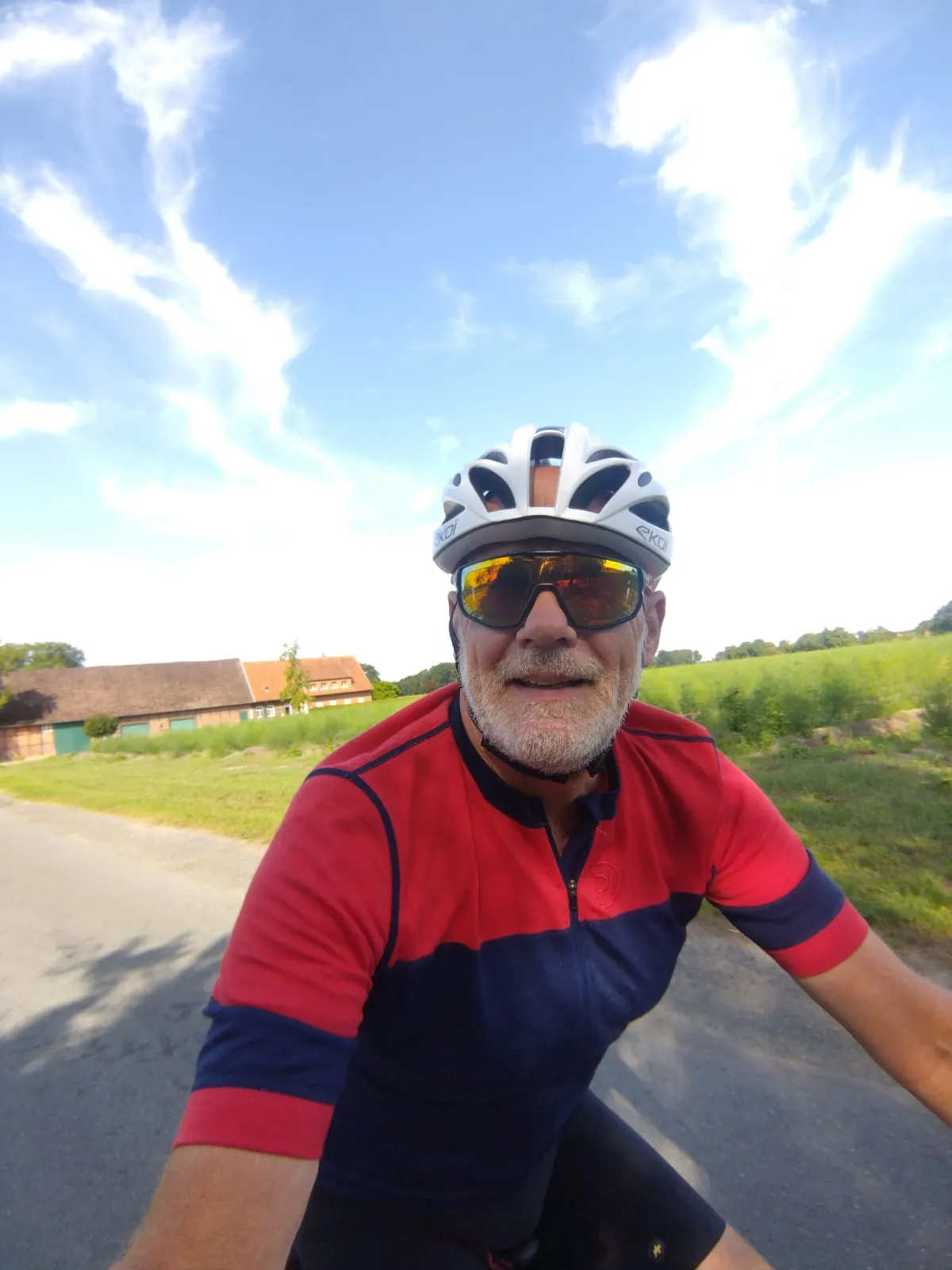 Jean-Pierre roule à vélo dans une campagne allemande, avec une ferme en arrière-plan