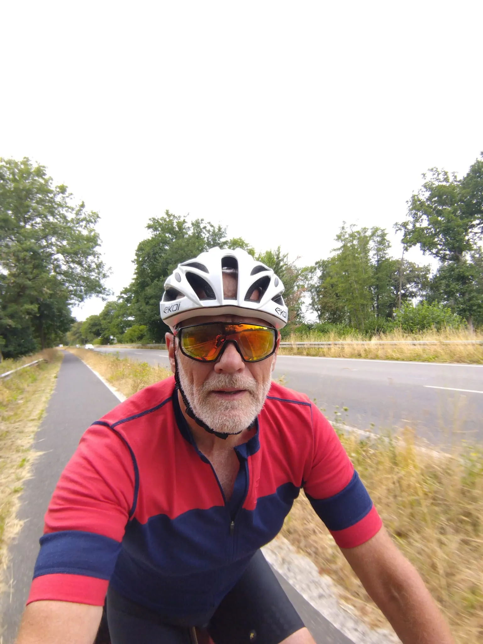 Jean-Pierre à vélo sur une piste cyclable bordée d’arbres