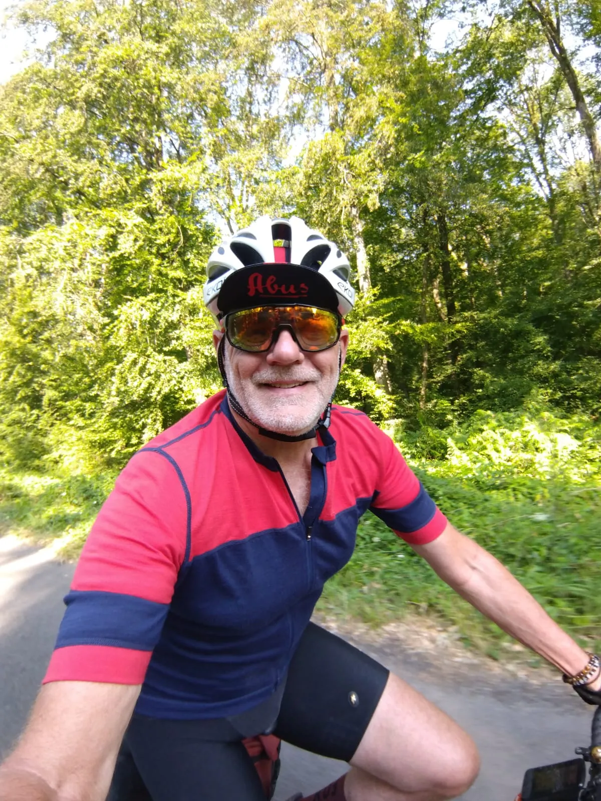 Jean-Pierre à vélo sur une petite route bordée d’arbres