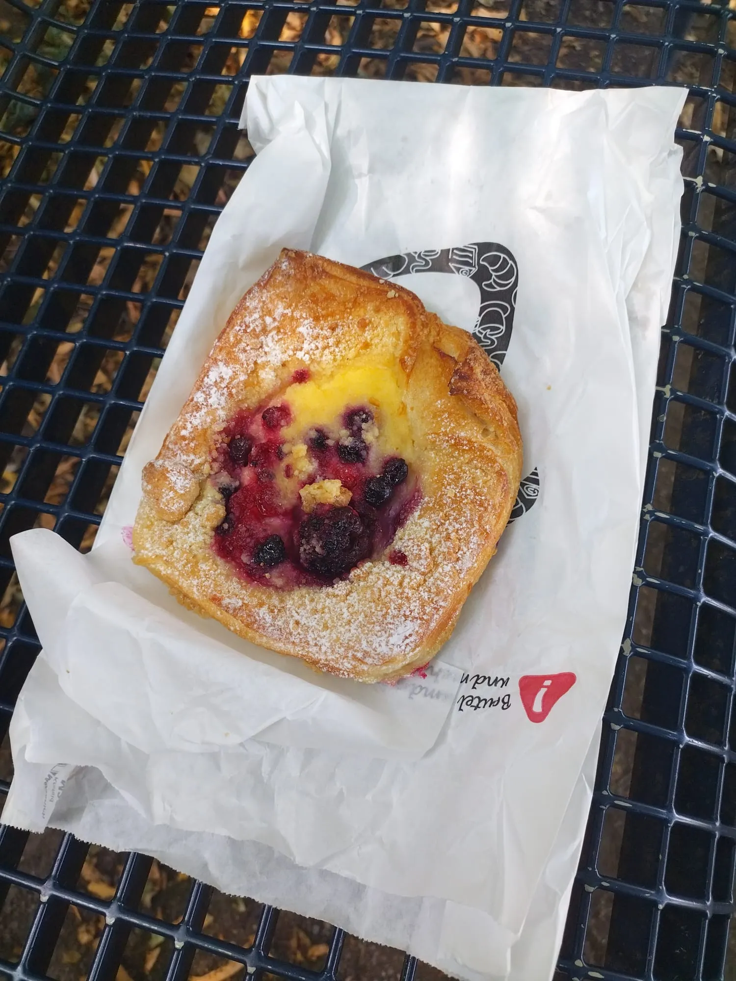 Une part de gâteau aux fruits rouges posée sur la table du banc