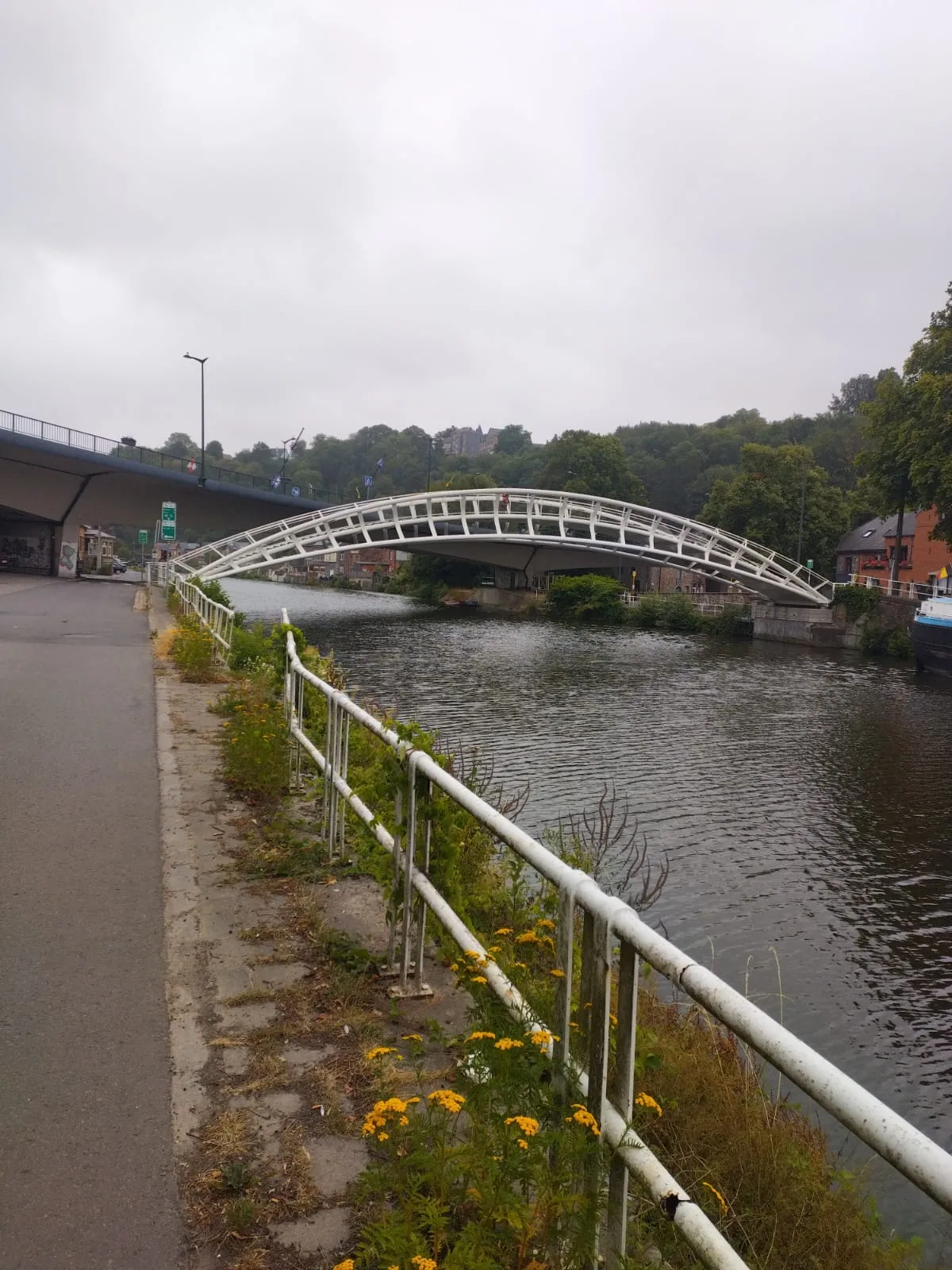 Une passerelle blanche franchissant la Sambre sous un ciel gris