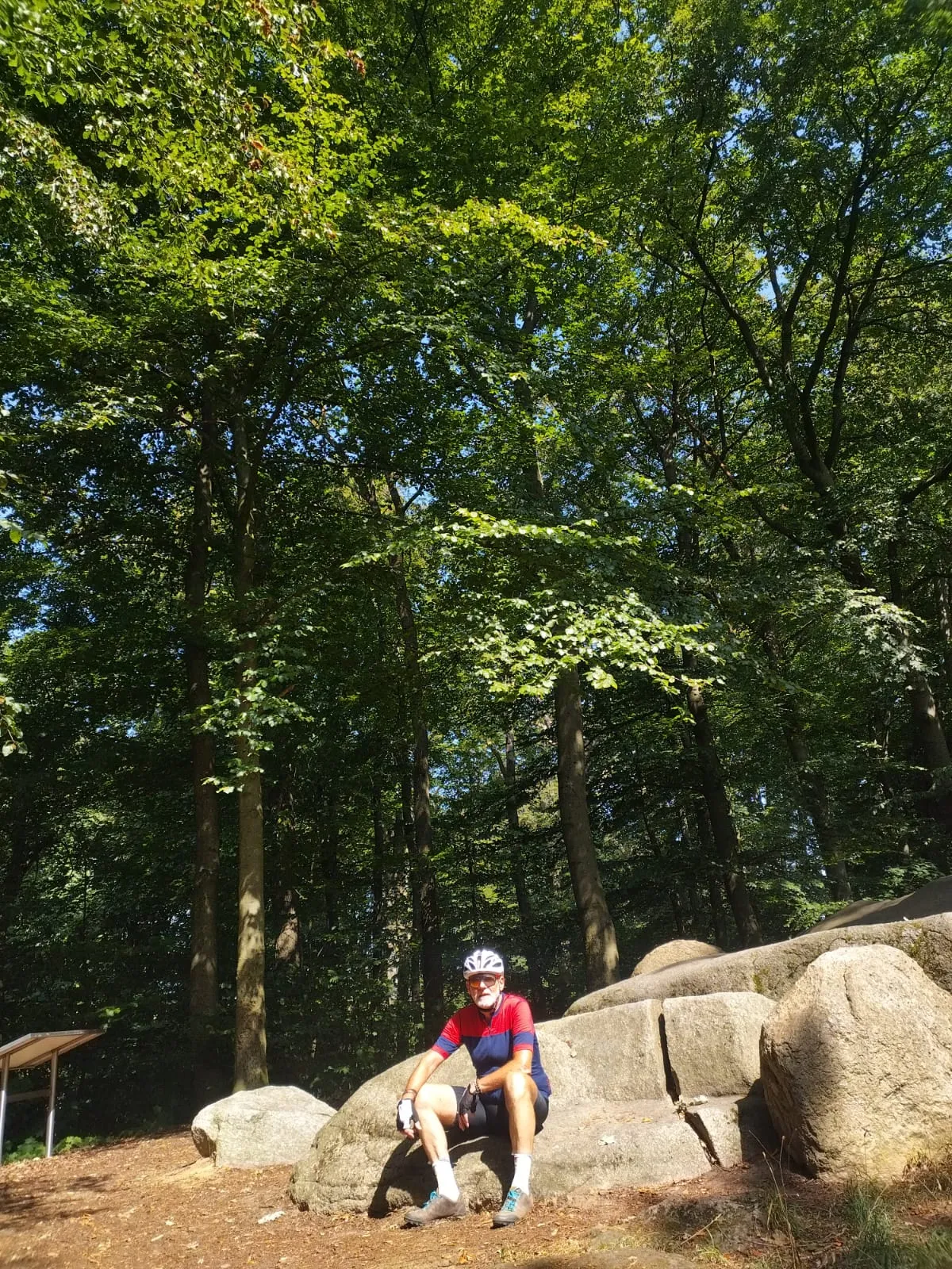 Jean-Pierre fait une pause assis sur des rochers dans une forêt