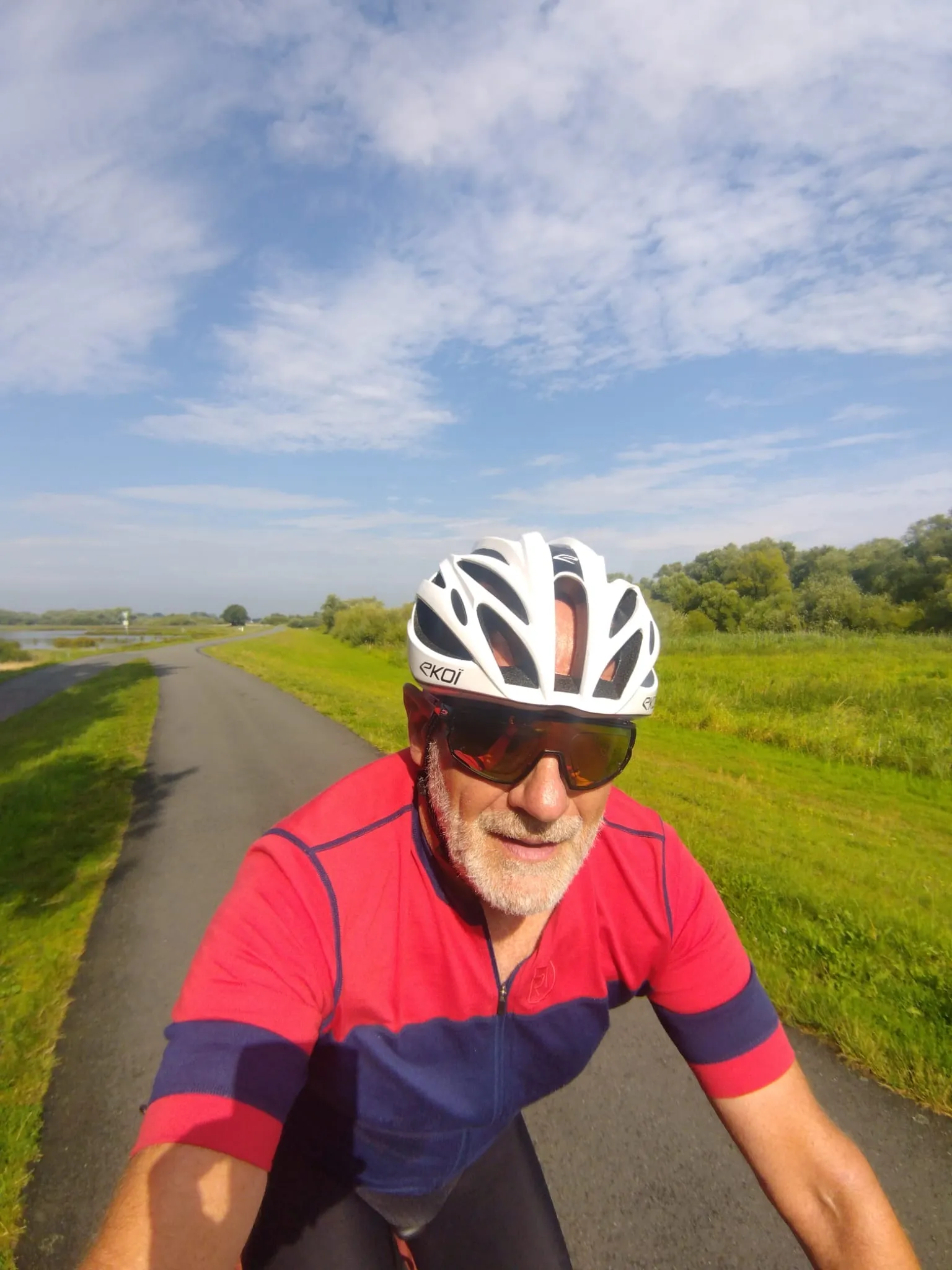 Jean-Pierre roule sur une piste au milieu des prairies, sous un ciel bleu