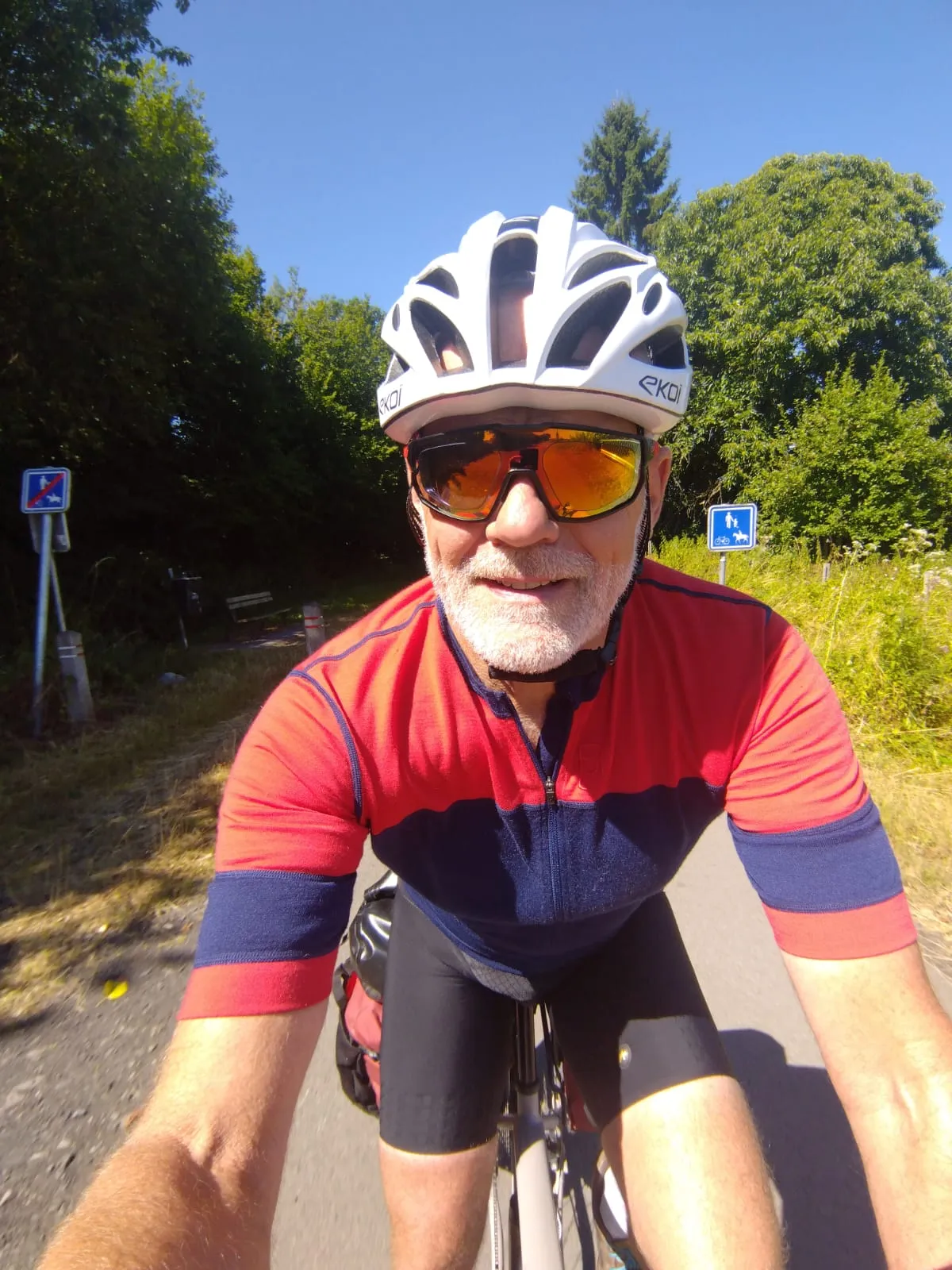 Jean-Pierre à vélo sur une route bordée d’arbres