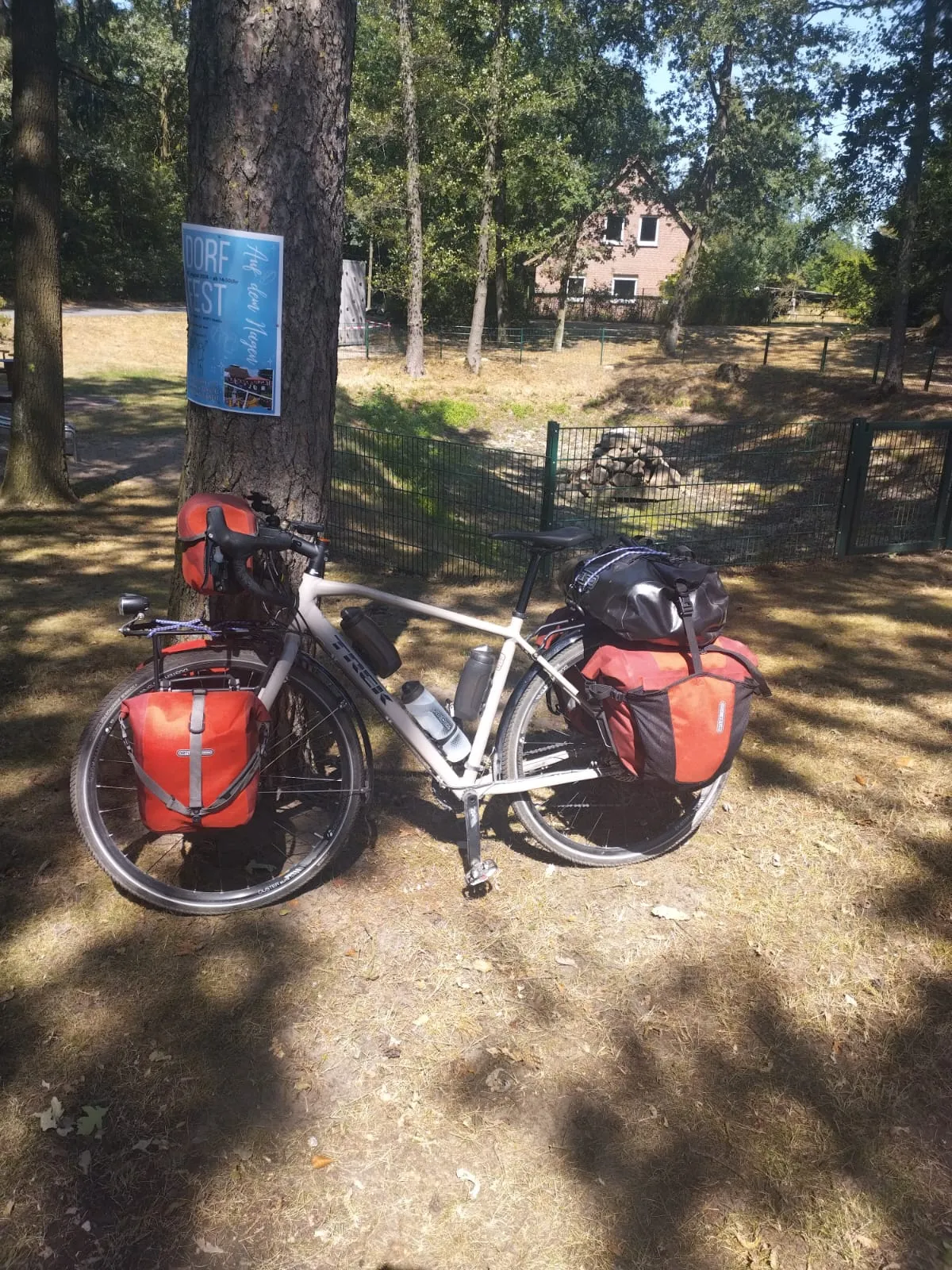 Le vélo chargé de Jean-Pierre est posé à l’ombre des arbres
