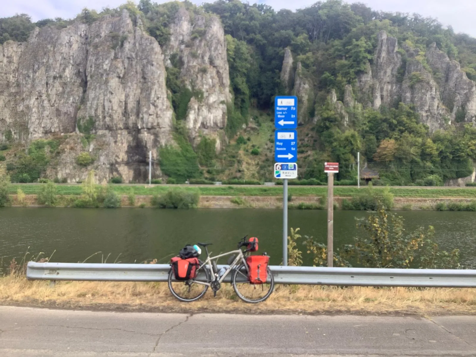 Le vélo chargé devant les rochers qui bordent la Meuse