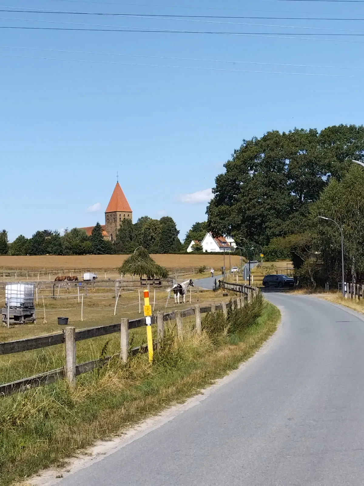 Une route descend vers un village allemand dominé par le clocher d’une église